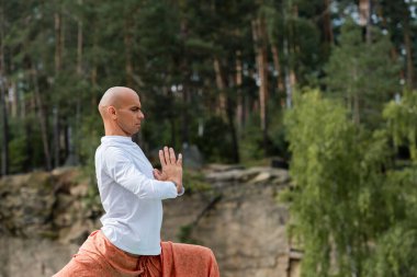 Beyaz kazaklı Budist ormanda dua eden ellerle meditasyon yapıyor.