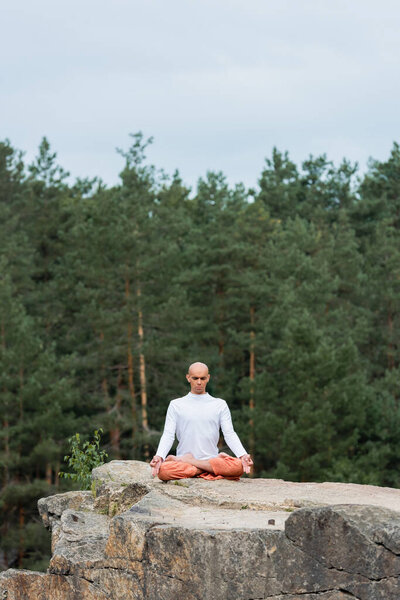 buddhist meditating in lotus pose with closed eyes outdoors
