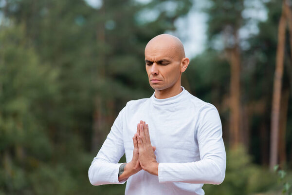 buddhist in sweatshirt praying with closed eyes outdoors
