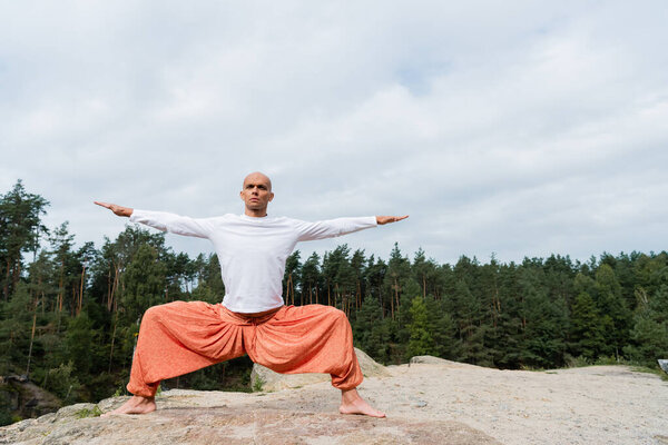 full length view of barefoot buddhist practicing goddess pose with outstretched hands