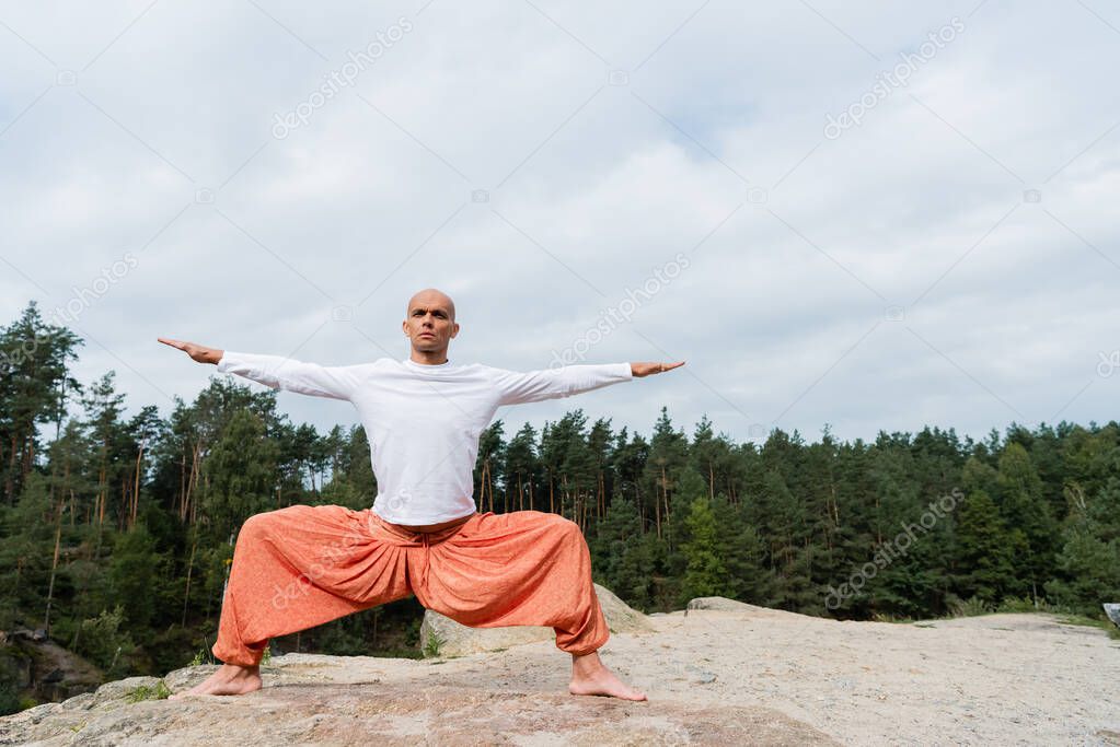 full length view of barefoot buddhist practicing goddess pose with outstretched hands