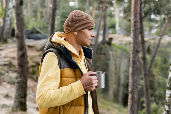 暖かいベストで観光客とビーニーは森の中で金属マグカップを持ち — ストック写真
