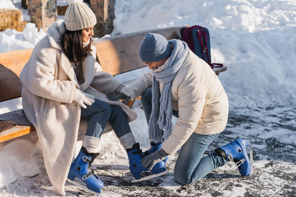 young man wearing ice skates on woman in winter hat