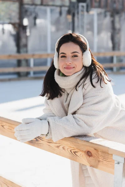 Happy Young Woman Ear Muffs Leaning Wooden Border Ice Rink — Stock Photo, Image