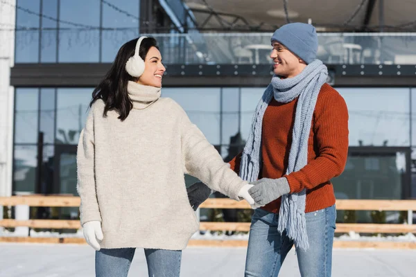 快乐的年轻女子 身穿燕尾服 与快乐的男朋友手牵手在冰球场上 — 图库照片