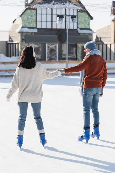 Brünette Junge Frau Ohrenschützer Hält Händchen Mit Fröhlichem Freund Auf — Stockfoto