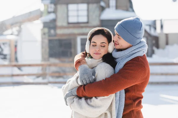 Feliz Hombre Abrazando Joven Mujer Orejeras Pista Hielo — Foto de Stock