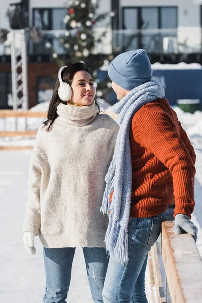 Sonriente Joven Mujer Orejeras Mirando Alegre Hombre Invierno Sombrero Apoyado —  Fotos de Stock