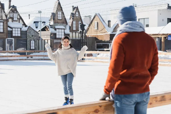 穿着冰鞋的快乐的年轻女子看着前景暗淡的男朋友 — 图库照片
