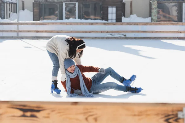 Glücklicher Mann Stürzt Beim Schlittschuhlaufen Auf Eisbahn Neben Frau — Stockfoto