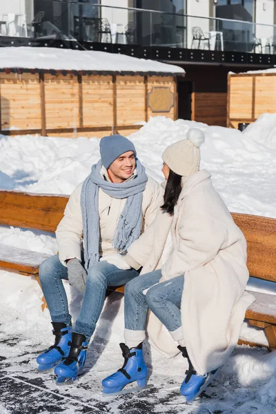 Fröhliches Junges Paar Mit Wintermützen Sitzt Auf Bank Eissporthalle — Stockfoto