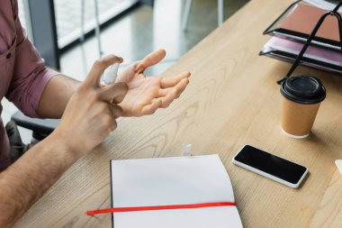 Akıllı telefonun yanında el dezenfektanı sıkan işadamlarının görüşü kesilmiş. Ofise gidip defter tutmak için kahve. 