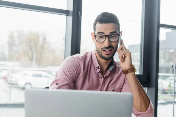 Gerente Musulmán Sonriente Hablando Teléfono Celular Cerca Borrosa Computadora Portátil — Foto de Stock