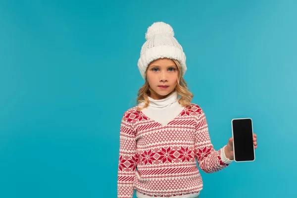 头戴针织帽子 头戴针织衫 头戴装饰品的孩子 展示智能手机 屏幕空白 蓝色孤立 — 图库照片