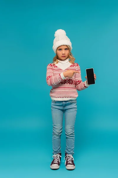 Child Knitted Hat Jumper Jeans Pointing Smartphone Blank Screen Blue — Stock Photo, Image