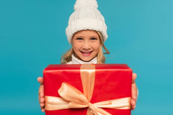 Cheerful Girl Knitted Hat Showing Blurred Gift Box Isolated Blue — Stock Photo, Image