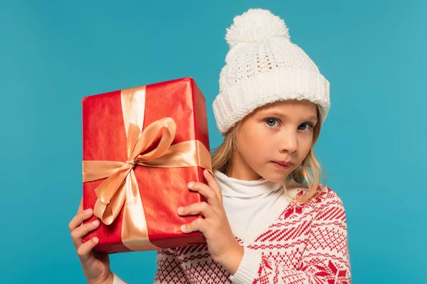 Kid Knitted Hat Sweater Looking Camera While Holding Red Gift — Stock Photo, Image