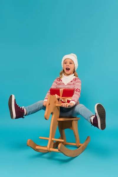 Cheerful Girl Warm Hat Shouting While Riding Rocking Horse Gift — Stock Photo, Image