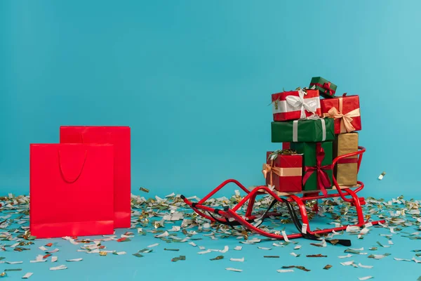 Trineo Con Cajas Regalo Multicolores Cerca Bolsas Compras Rojas Azul —  Fotos de Stock