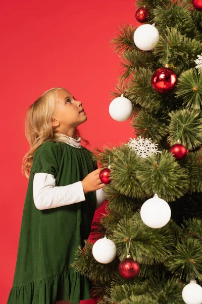 Yeşil Elbiseli Kız Kırmızıda Izole Edilmiş Noel Ağacına Bakıyor — Stok fotoğraf