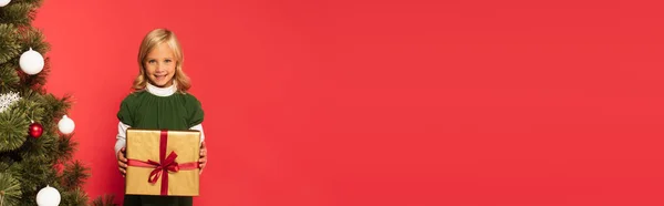 Счастливая Девушка Держит Подарок Рядом Украшенной Елкой Изолированы Красный Баннер — стоковое фото