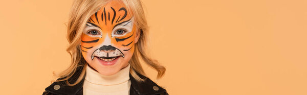 pleased girl in tiger makeup smiling at camera isolated on beige, banner