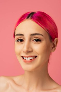 Renkli saçlı neşeli genç bir kadın pembe üzerinde izole bir şekilde gülümsüyor. 