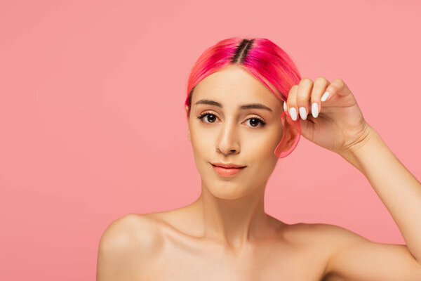 young woman with colorful hair holding moisturizing eye patch isolated on pink 