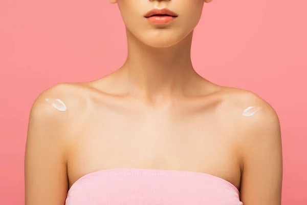 cropped view of young woman with lotion on bare shoulders isolated on pink