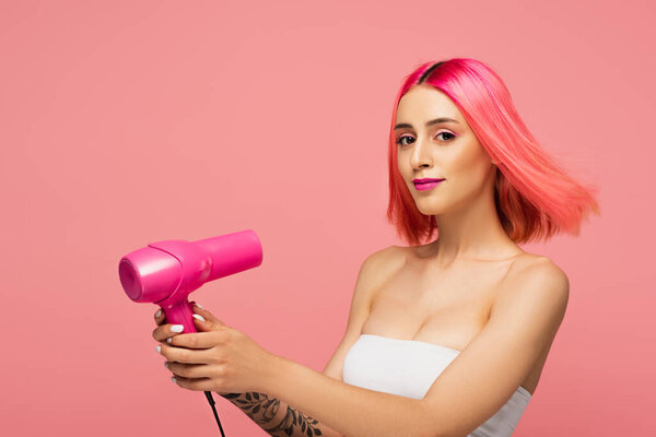 pretty young woman with colorful hair holding hair dryer isolated on pink 