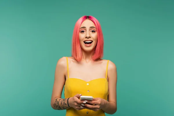 红褐色头发的兴奋的年轻女人拿着用绿松石隔开的智能手机 — 图库照片