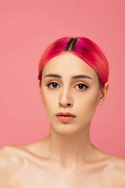 pretty young woman with colorful hair and makeup looking at camera isolated on pink 