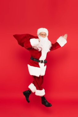Noel Baba, elinde torbayla kırmızı renkte havada asılı duruyor. 