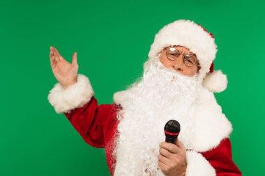 Mikrofonlu Noel Baba yeşile el izole edilmiş.