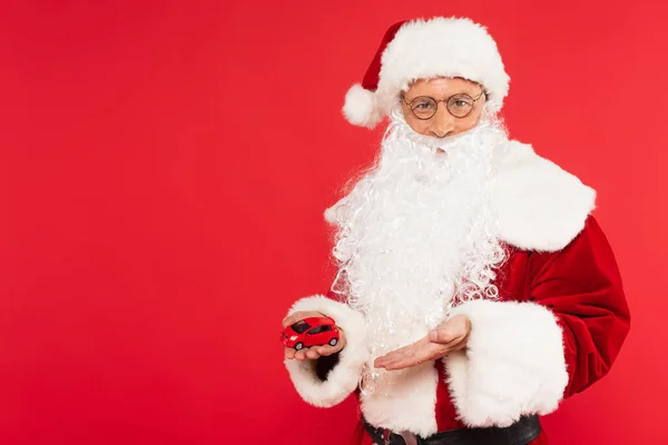 Papai Noel Chapéu Óculos Apontando Para Modelo Carro Isolado Vermelho — Fotografia de Stock