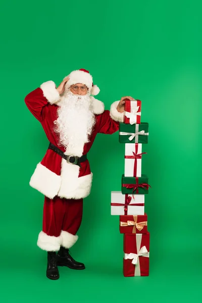 Preocupado Santa Claus Pie Cerca Regalos Apilados Sobre Fondo Verde —  Fotos de Stock