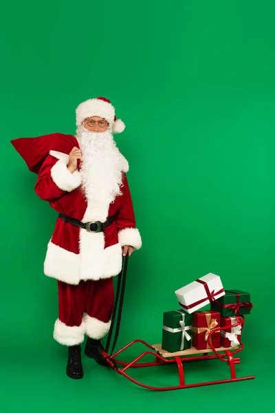 Santa Claus Zsák Áll Közel Szán Ajándékokkal Zöld Háttér — Stock Fotó