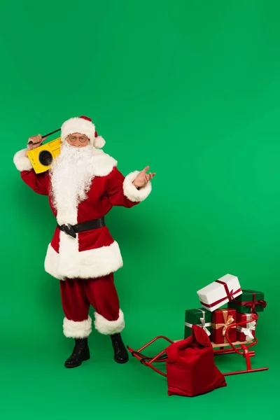 Santa Claus Boombox Áll Ajándékok Közelében Szán Zsák Zöld Háttér — Stock Fotó