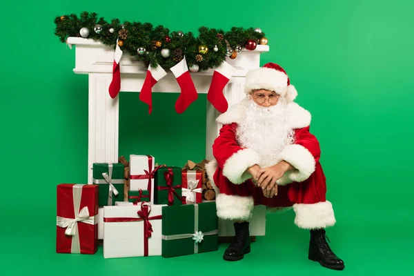 Santa Claus Looking Camera Gifts Decorated Fireplace Green Background — Stock Photo, Image