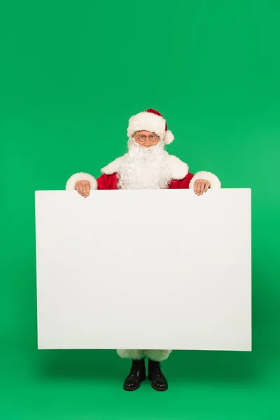 Santa Claus Holding Placard Copy Space Looking Camera Green Background — Stock Photo, Image