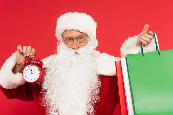 Santa Claus Con Despertador Bolsas Compras Mirando Cámara Aislada Rojo — Foto de Stock