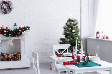 Modern oturma odası, dekore edilmiş şöminesi, Noel ağacı ve şenlikli akşam yemeği için servis edilen masa.