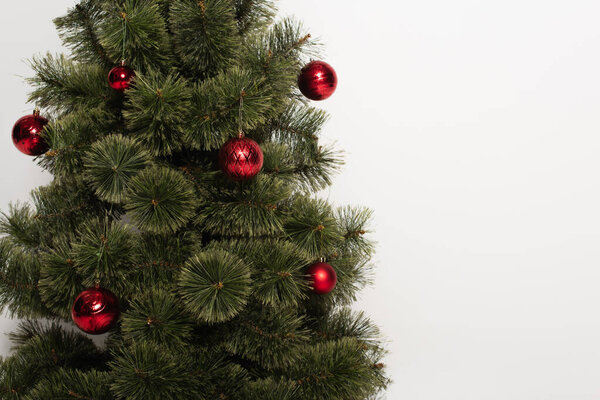green pine tree decorated with red and shiny christmas balls isolated on white