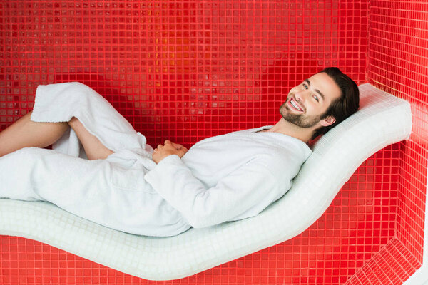 Positive man relaxing on lounge chair in spa center 