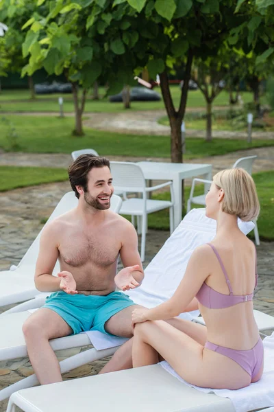 Happy Man Swimming Trunks Talking Girlfriend Deck Chair Resort — Stock Photo, Image