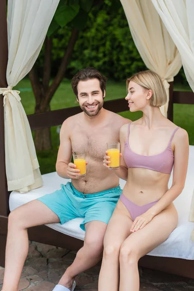 Casal Sorridente Com Suco Laranja Sentado Cama Lounge Resort — Fotografia de Stock