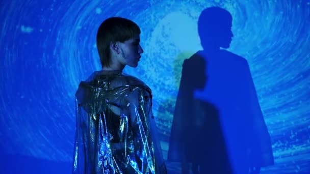 抽象的な青の背景でカメラを向けるスタイリッシュな女性のスローモーション — ストック動画
