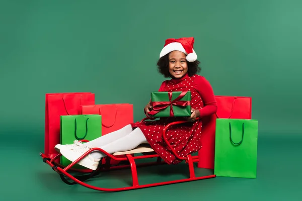 Afroamerikanerin Mit Weihnachtsmütze Hält Geschenk Der Hand Während Sie Auf — Stockfoto