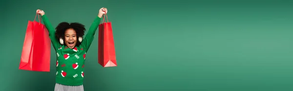 Excited African American Girl Ear Muffs Sweater Holding Shopping Bags — Stock Photo, Image