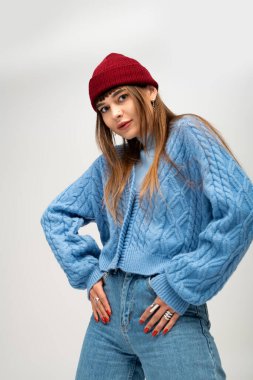 Tarz sahibi genç bir kadın hafif bir arka planda etkin bir şekilde poz verir..